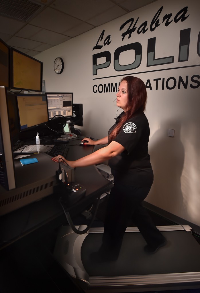Amanda Enslow, communications operator for the La Habra PD, keeps active as she walks on a treadmill while taking calls in the 911 Communications Division dispatch center. Photo by Steven Georges/Behind the Badge OC
