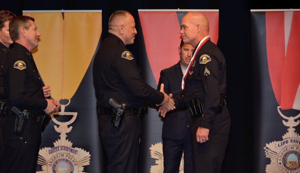 Officer Erik Degn, right, is congratulated by Anaheim Police Chief Raul Quezada as Degn receives the Lifesaving Award. Behind them is Eric Anderson. Photo by Steven Georges/Behind the Badge OC