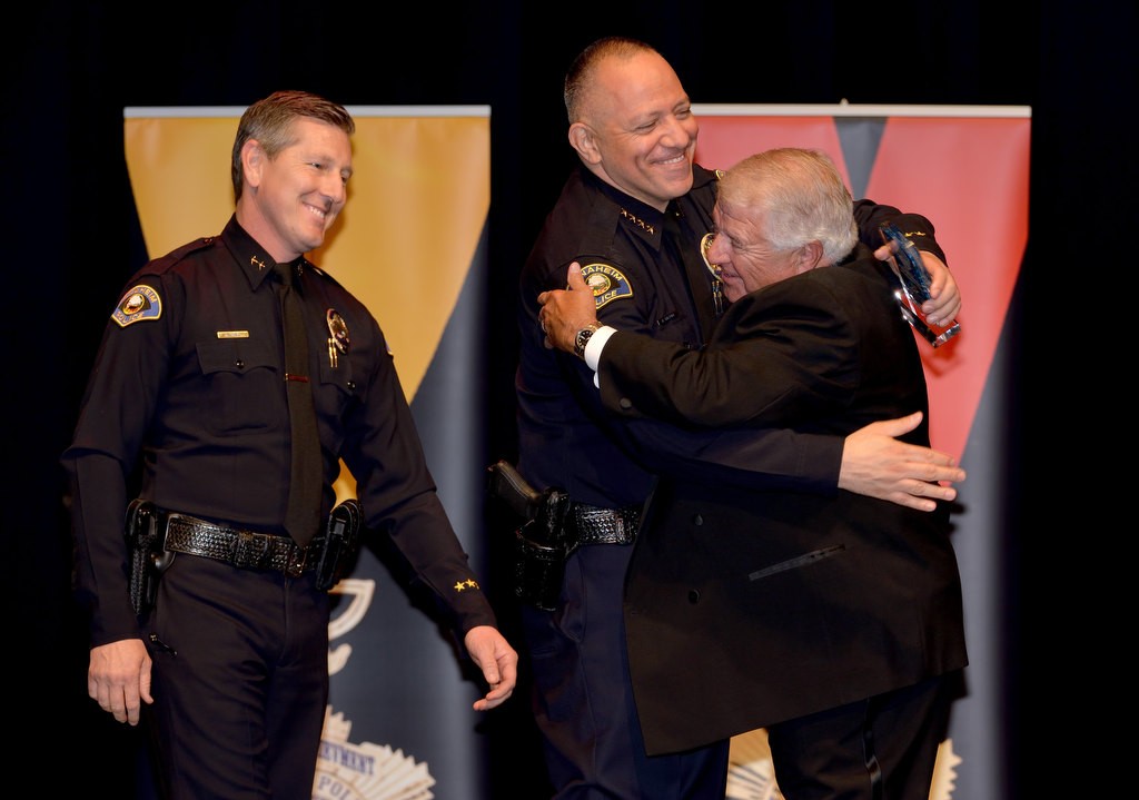 Program Master of Ceremonies Michael Villani receives a hug from Anaheim Police Chief Raul Quezada with Deputy Chief Dan Cahill, left, as Villani receives the Reserve Officer of the Year award. Photo by Steven Georges/Behind the Badge OC