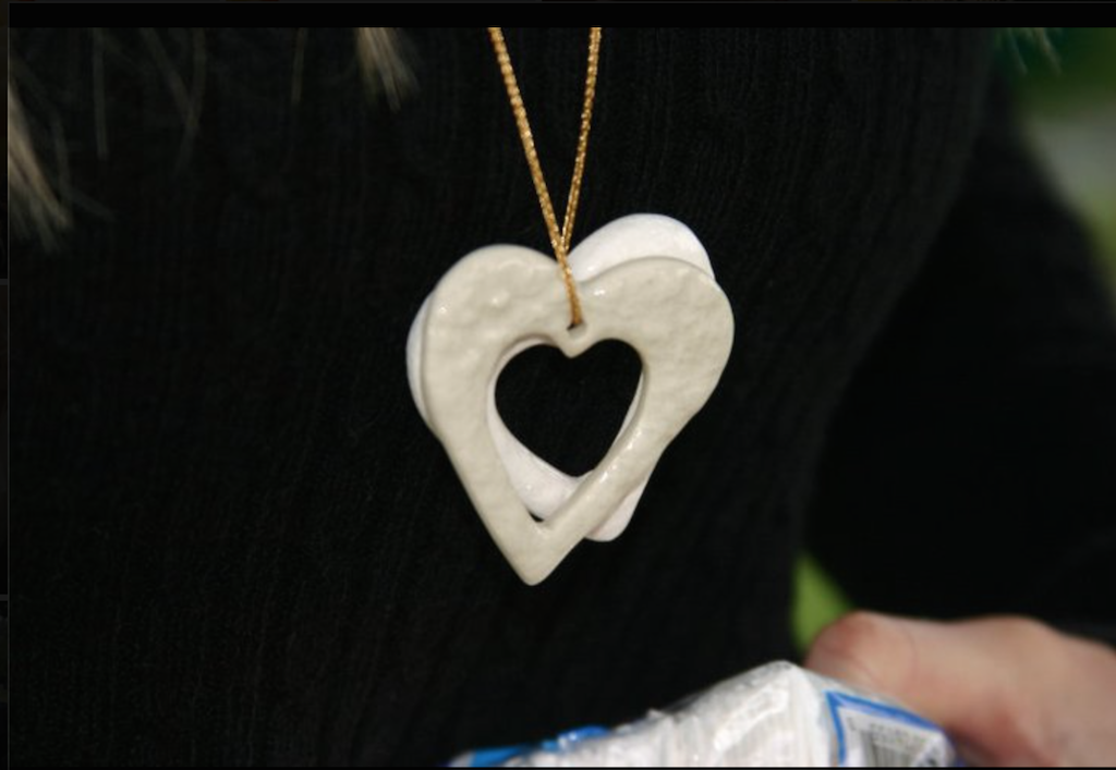 Catherine Avila wears two ceramic heart around her neck to remember her children, Jimmy and Milena. A smaller cream-colored ceramic heart was buried with each of her children.  This necklace is one of the items she puts in Box of Hope to help grieving families who have lost children. Photo courtesy the Avila family. 