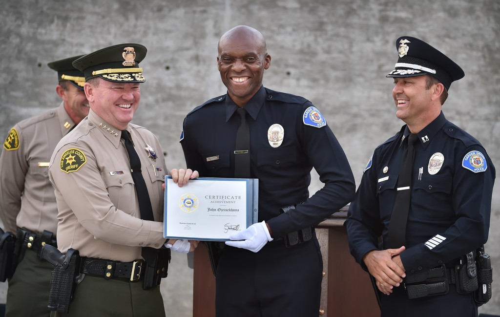 Los Angeles County Sheriff Jim McDonnell, left, and Garden Grove PD Capt. Kevin Boddy, right, present GGPD Reserve Officer John Ojeisekhoba an award for achieving top scores in physical training, academics, leadership and other areas at the LA Sheriff Department’s Biscailuz Training Academy. Photo by Steven Georges/Behind the Badge OC