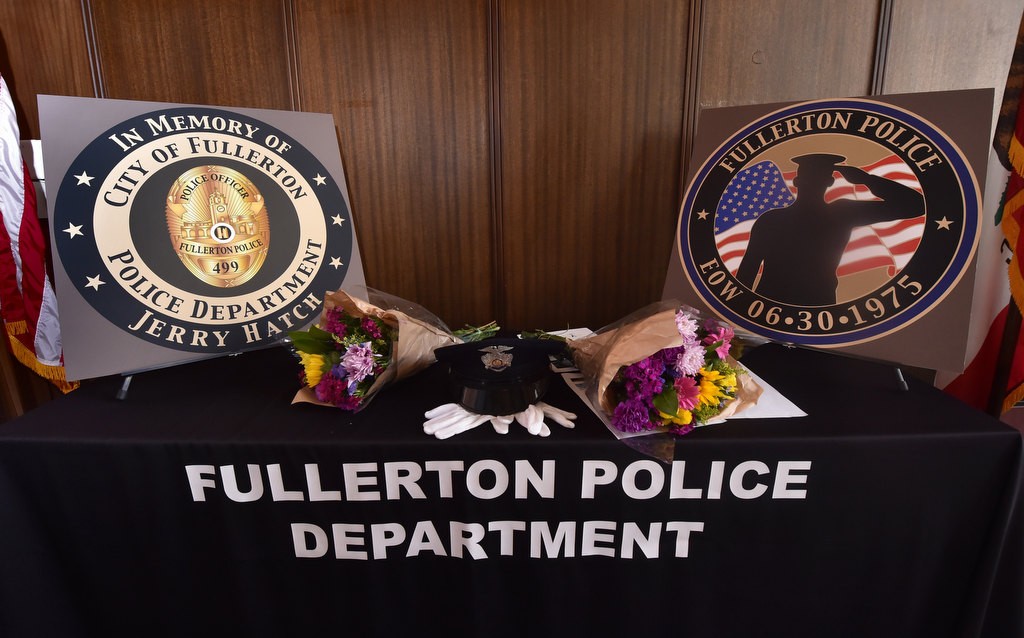 A police cap, flowers and poster boards showing the design of the new challenge coin honoring Officer Jerry Hatch, the first Fullerton PD officer to be killed in the line of duty, are displayed during a remembrance gathering at the Fullerton PD. Photo by Steven Georges/Behind the Badge OC