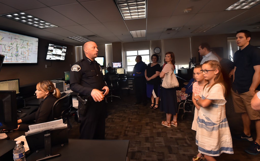 Fullerton PD Chief Dan Hughes gives a tour of the dispatch center to family members of fallen Officer Hatch, with Dispatcher xxx Garcia, left. Photo by Steven Georges/Behind the Badge OC