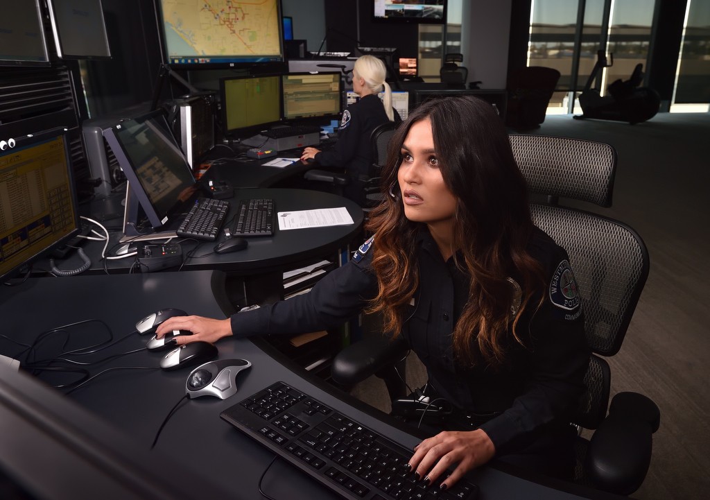 Melorie Madrid of the Westminster PD looks up at the multiple screens as she takes calls at the department’s dispatch center. Behind her is Dispatcher Erica Marlow. Photo by Steven Georges/Behind the Badge OC
