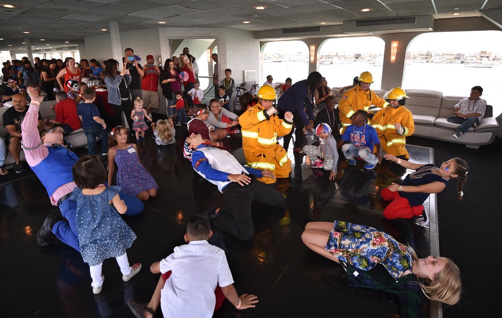 Orange County Sheriff deputies dressed in their official fire outfits and entertainment managers from Farrell's Ice Cream dance with Make-a-Wish kids on board the Electra Cruises boat Eternity during a 4th of July Newport Harbor Cruise. Photo by Steven Georges/Behind the Badge OC