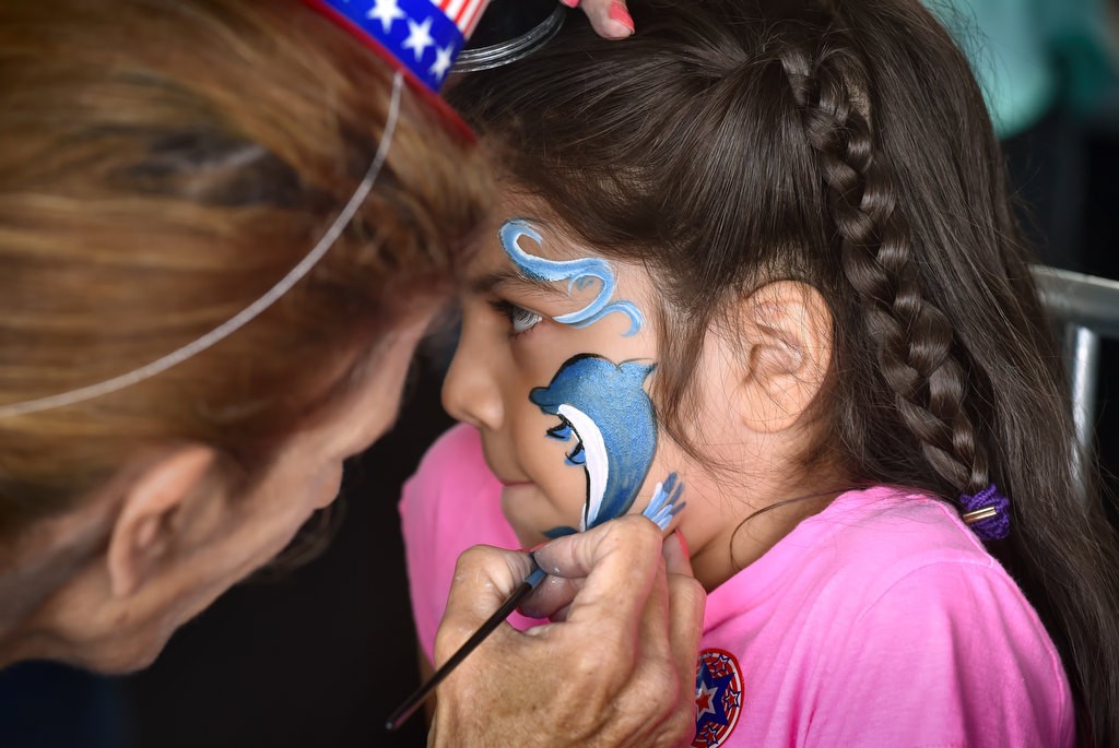 Hazel Barajas, 7, gets a dolphin painted on her face by Carol Beyer of “Fantastik Faces” during the 4th of July Newport Harbor Cruise. Photo by Steven Georges/Behind the Badge OC