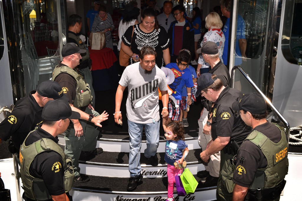 Orange County Sheriff deputies helps kids off the Electra Cruises boat Eternity at the end of a Make-a-Wish 4th of July Newport Harbor Cruise. Photo by Steven Georges/Behind the Badge OC