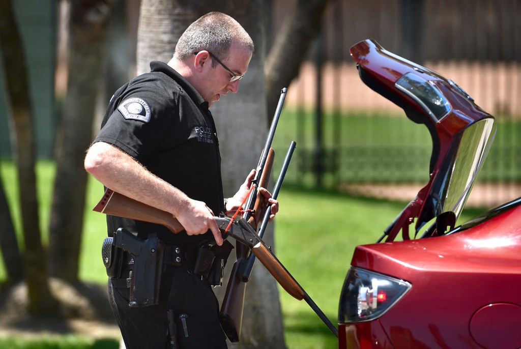 Sgt. Nathan Stauber removes rifles from the trunk of a car during Anaheim PD’s gun buyback at La Palma Park in Saturday. Participants, who receive a $100 gift card for bringing in a gun, were required to arrive with the guns in the trunk, unloaded and with the safety on. Photo by Steven Georges/Behind the Badge OC