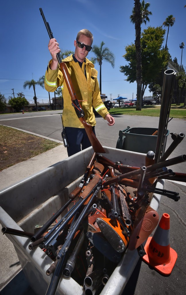 Anaheim Firefighter John Strickland places a rifle collected from a gun buyback event at La Palma park into a storage bin with other weapons collected that day. The buyback program on Saturday was so successful that police started handing out IOU’s when they ran out of the $100 gift cards they were issuing in exchange for guns turned in. Photo by Steven Georges/Behind the Badge OC