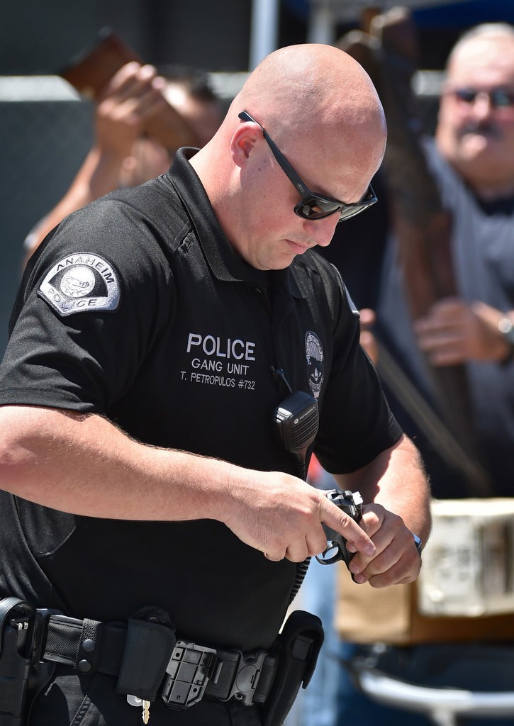 Officer Ted Petropulos rechecks a handgun for safety after receiving it from the public during an anonymous gun buyback program at La Palma park. Photo by Steven Georges/Behind the Badge OC