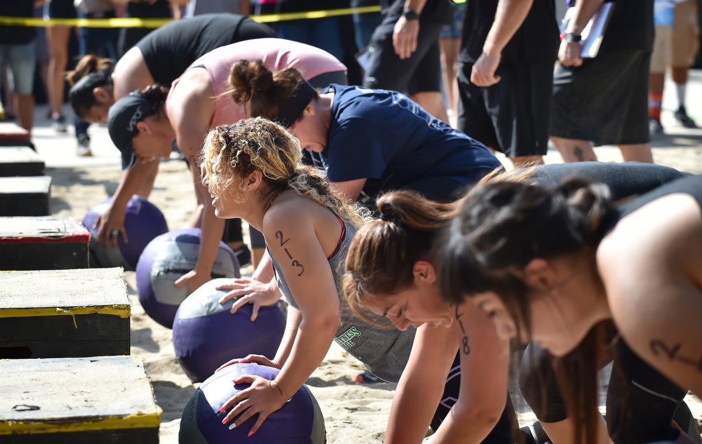 Women, including Jonnelle Cato, center, do pushups on both sides of a block while carrying a medicine ball during timed competition for the OCSD Women’s Fitness Challenge. Photo by Steven Georges/Behind the Badge OC