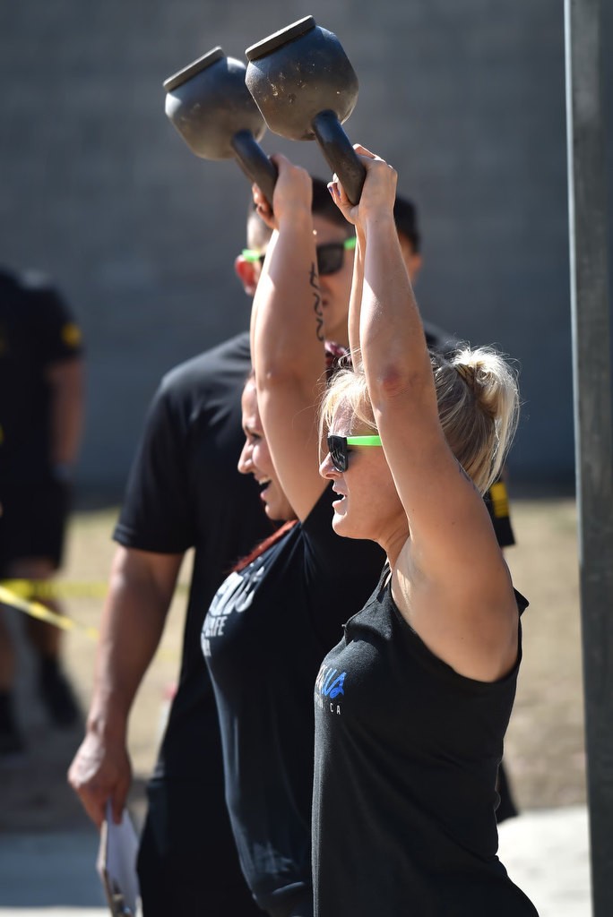 Justine Collins, left, and Jenna Byers swings weights above their heads during timed competition for the OCSD Women’s Fitness Challenge. Photo by Steven Georges/Behind the Badge OC