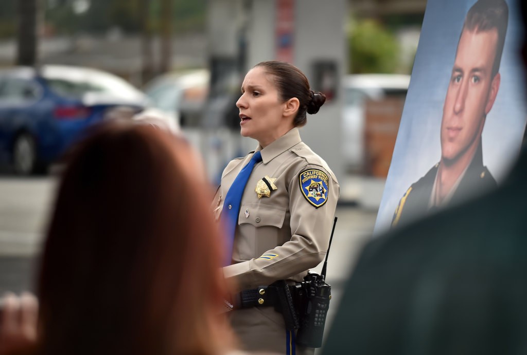 CHP Officer Hope Maxon sings during the 20th anniversary memorial remembrance ceremony for CHP Officer Don Burt, photo at right, who was killed at that location in Fullerton on July 13, 1996 while making a traffic stop that started from the 57 freeway next to the gas station. Photo by Steven Georges/Behind the Badge OC