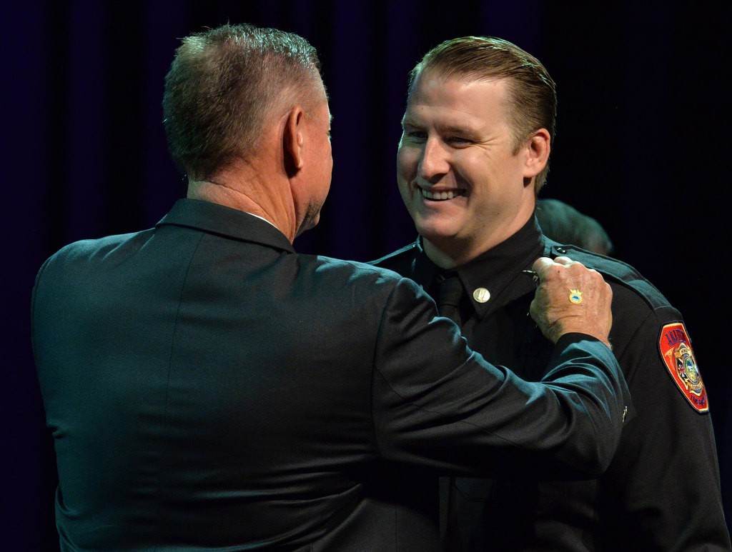 Captain Grant Riley receives his new badge from his father Timothy Riley, retired fire chief from Newport Beach Fire Department and formerly a deputy chief for Anaheim Fire, during the Anaheim Fire & Rescue Promotion and Graduation ceremony. Photo by Steven Georges/Behind the Badge OC