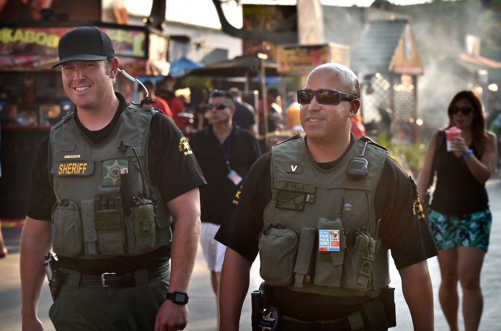 OC Sheriff deputies Chris Emerson, left, and Dan Villa walk the grounds as the sun starts to set on a hot day at the Orange County Fair. Photo by Steven Georges/Behind the Badge OC
