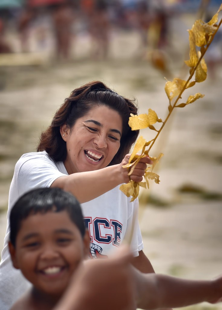 Rocio Lopez uses seaweed found on the beach to let kids play jump rope during an Orange County Family Justice Center Foundation filed trip to Laguna Beach. Photo by Steven Georges/Behind the Badge OC