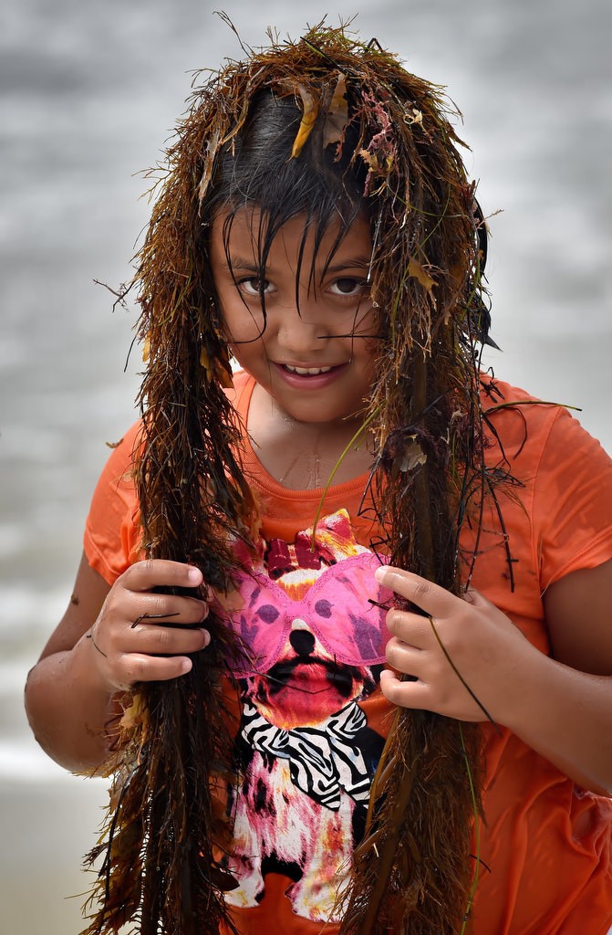 Ten-year-old Carina Sanchez of Anaheim uses seaweed for a wig during a free play time for kids from an Orange County Family Justice Center Foundation field trip to Laguna Beach. Photo by Steven Georges/Behind the Badge OC