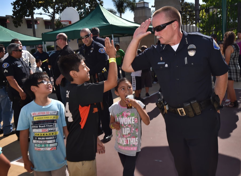 Emmanuel Mateo, 10, gives a high-five to Garden Grove PD Chief Todd Elgin after a bean bag challenge, part of National Night Out at Buena Clinton Youth & Family Center. Photo by Steven Georges/Behind the Badge OC