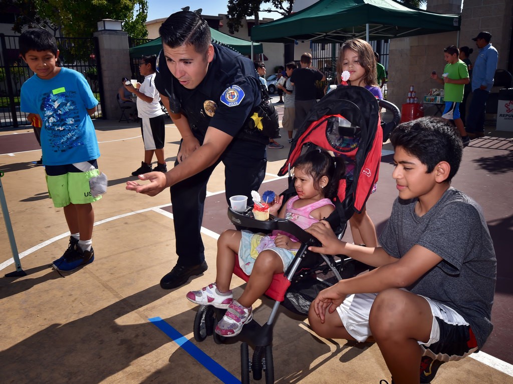 Garden Grove PD Officer Joshua Escobedo tosses beanbags with 3-year-old Juliet Morales and her brother Angel Morales during Garden Grove PD's National Night Out. Photo by Steven Georges/Behind the Badge OC