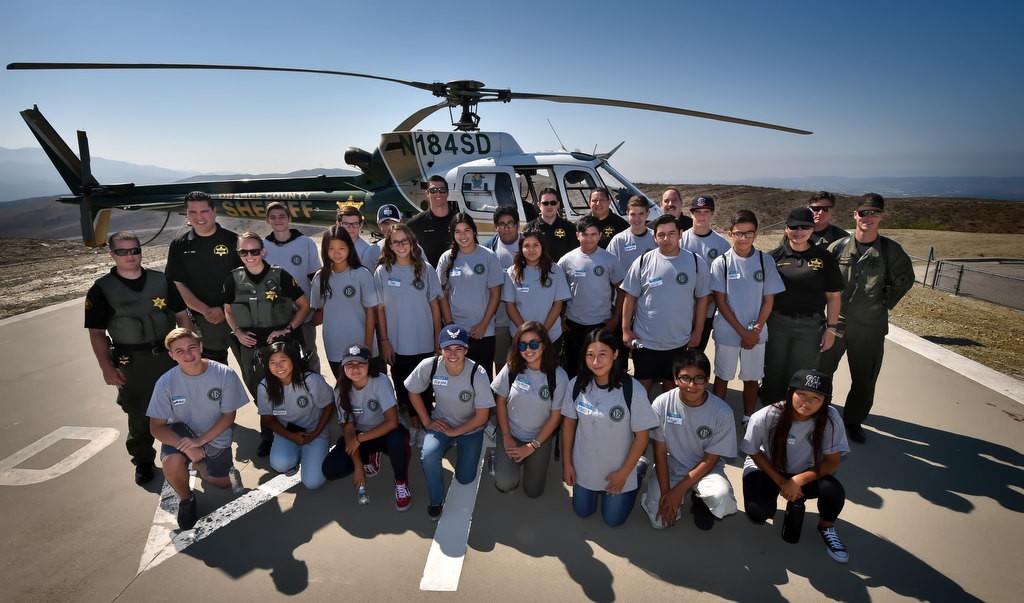 Members of the OC Sheriff Department’s Youth Citizens’ Academy take a group photo in front of the OC Sheriff’s helicopter Duke 2 during a tour of the Loma Ridge Emergency Operations Center. Photo by Steven Georges/Behind the Badge OC