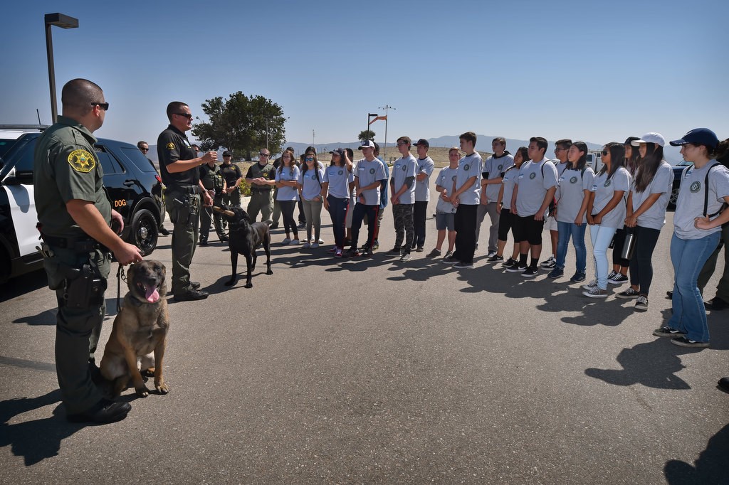 OC Sheriff Deputy Carpenter with his K-9 partner Reiko, left, and Deputy Ryan Buhr with his K-9 partner Conan talk to kids from the Orange County Sheriff Youth Citizens’ Academy about the K-9 department during a tour at Loma Ridge. Photo by Steven Georges/Behind the Badge OC