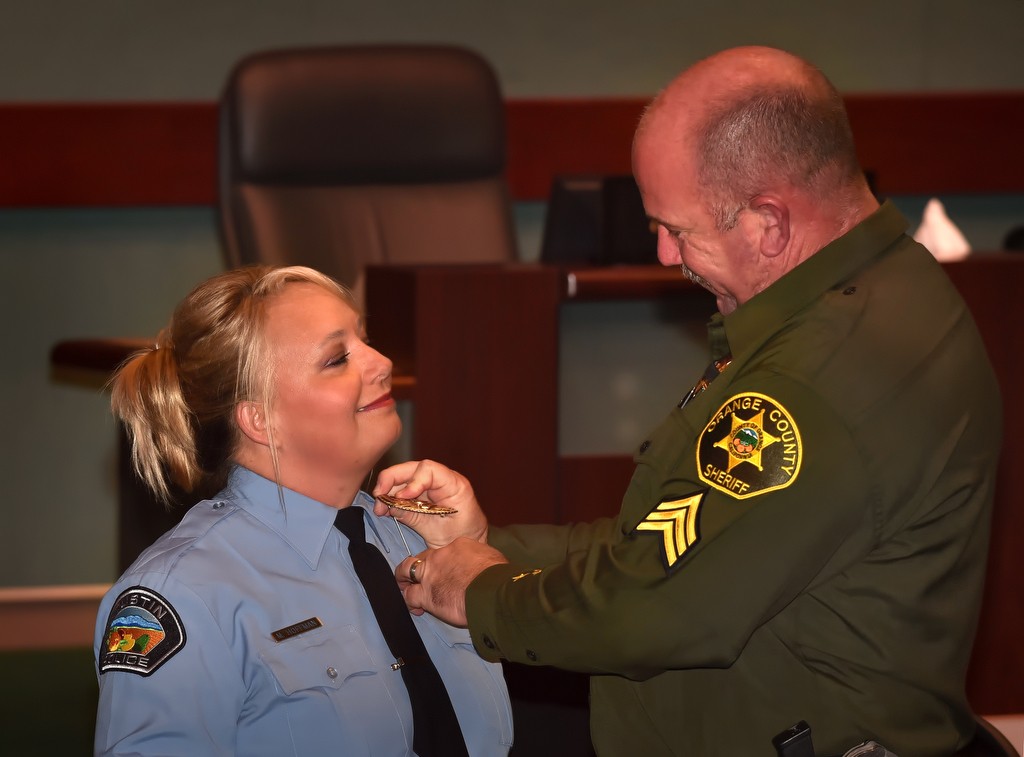 Tustin PD Communications Officer Melinda Hoffman gets her badge pinned to her by her husband, James of the OC Sheriff Department, during a promotions and swearing in ceremony. Photo by Steven Georges/Behind the Badge OC