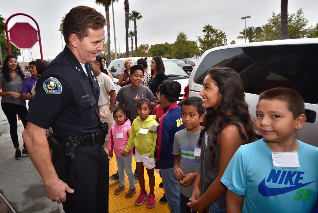 Anaheim PD Deputy Chief Julian Harvey greets kids, including Yesenia, 12, second from right, as they arrive at the Target store for back to school shopping. Photo by Steven Georges/Behind the Badge OC