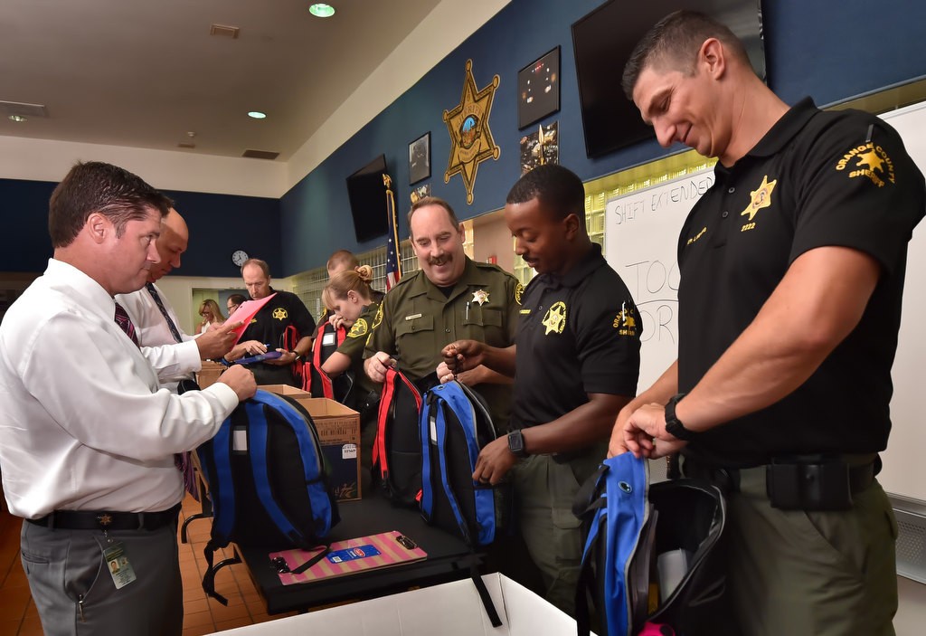 Lt. Mark Stichter, left, Sgt. Mike Pixomatis, Dep. C. Anderson and Dep. Jonathan Nehrig volunteer their time to fill backpacks with school supplies that will be donated to Orange County kids in need. Photo by Steven Georges/Behind the Badge OC