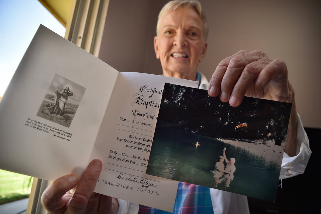 Alice Chandler, 88, holds her baptism certificate and photo for when, in 1975, she was baptized in the Jordan River in Israel. Photo by Steven Georges/Behind the Badge OC