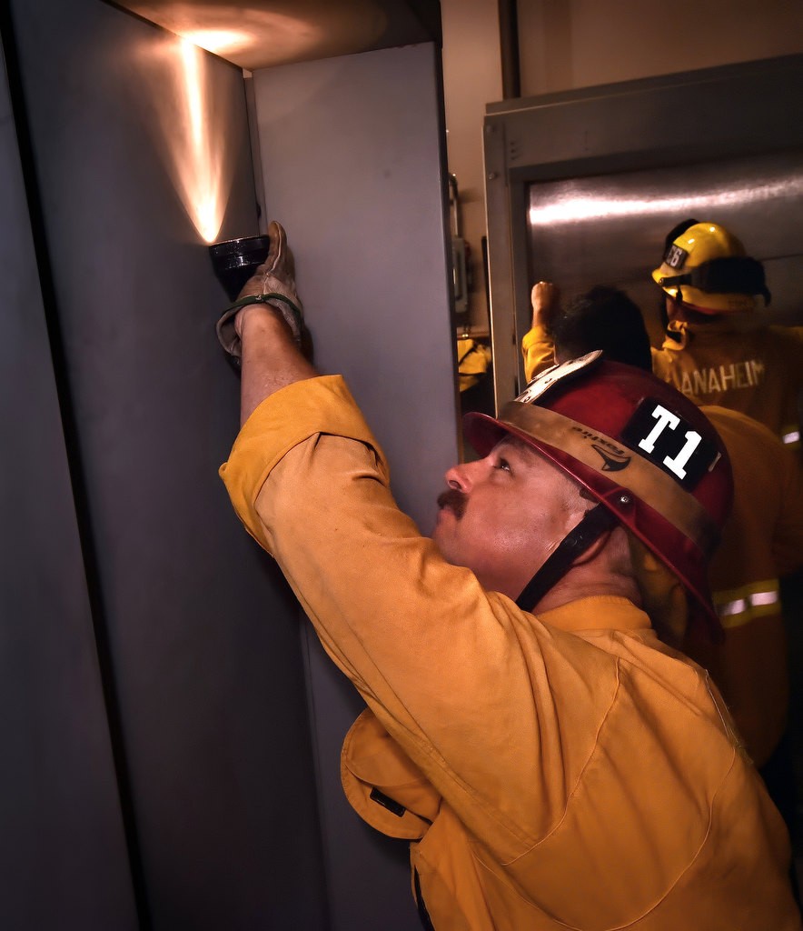 Capt. John Lesovsky of Anaheim Fire & Rescue looks for the spot to insert a special tool to unlocks the doors of an elevator during a training session. Photo by Steven Georges/Behind the Badge OC