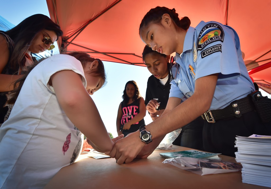 Tustin PD Explorer Marleen Ramirez helps Joanna Carabarin, 7, of Tustin, as she creates a fingerprint card for her parents to keep during a re-dedication of Frontier Park. Photo by Steven Georges/Behind the Badge OC