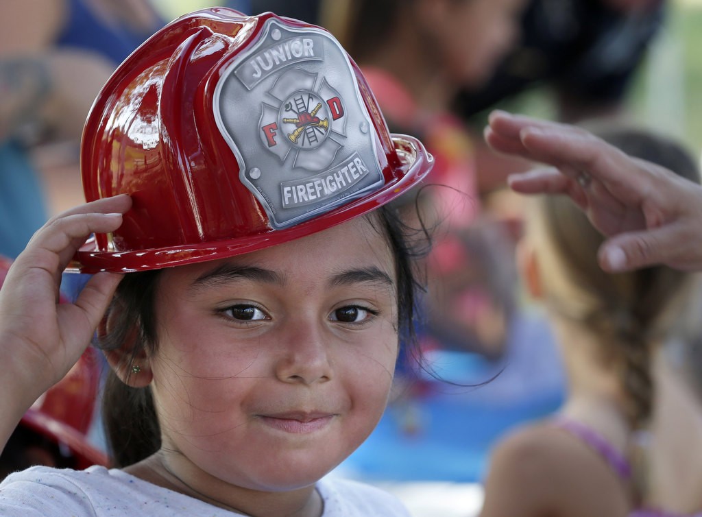 Seven year-old Natali Gutierrez proudly wears a fire fighter helmet at the  Fullerton Police Department's National Night Out at Independence Park. Photo by Christine Cotter