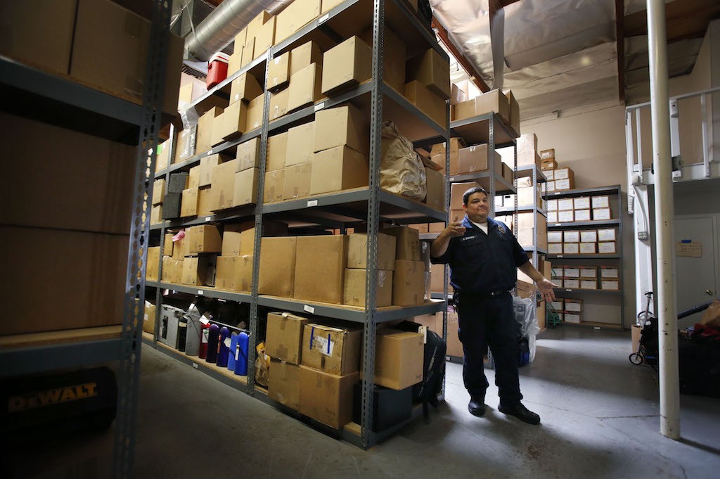 Stacks of boxes filled with evidence tower over Garden Grove PD's Eric Quintero in the departments' evidence locker.  Photo by Christine Cotter