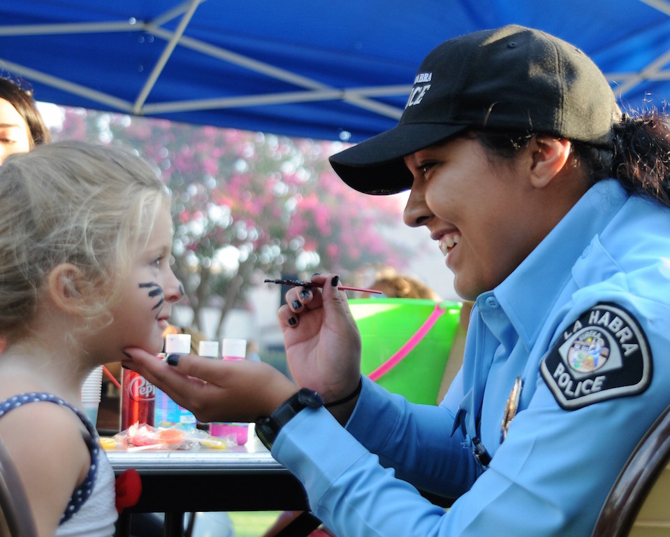 La Habra PD Police Services Aide Larissa Terrones paints the face of 3-year old Adela during the National Night Out event held Aug. 2 at Portola Park. Photo by: Lou Ponsi/Behind the Badge OC 