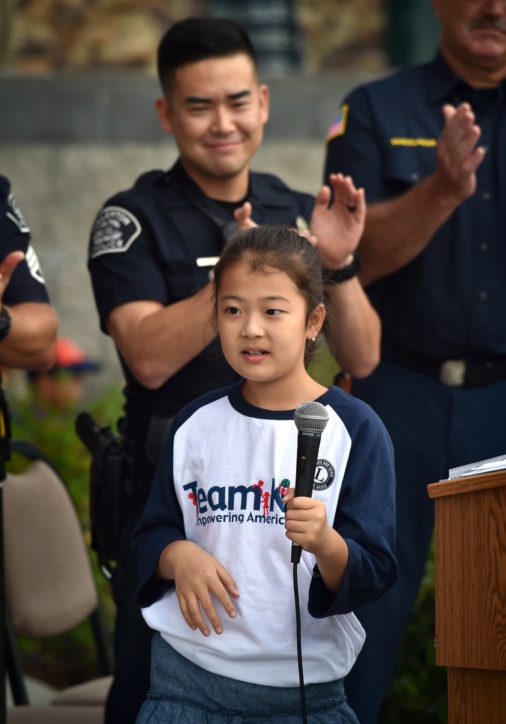 Susie Kim, 10, after reading a speech she wrote called Welles Crowther, The Man in the Red Bandana, during a 9-11 assembly at Fisler Elementary School. Behind her is Fullerton PD Officer Michael Yang. Photo by Steven Georges/Behind the Badge OC