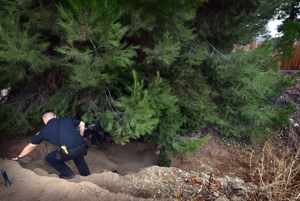 La Habra PD Officer Justin Braasch walks down a hill to check-in on a homeless couple living under a tree in a flood canal. Photo by Steven Georges/Behind the Badge OC