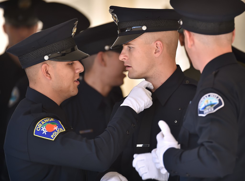 Orange PD recruit Anthony Castaneda, left, adjusts the tie of a classmate before Golden West College Criminal Justice Training Center graduation ceremonies at Orange Coast College. Photo by Steven Georges/Behind the Badge OC