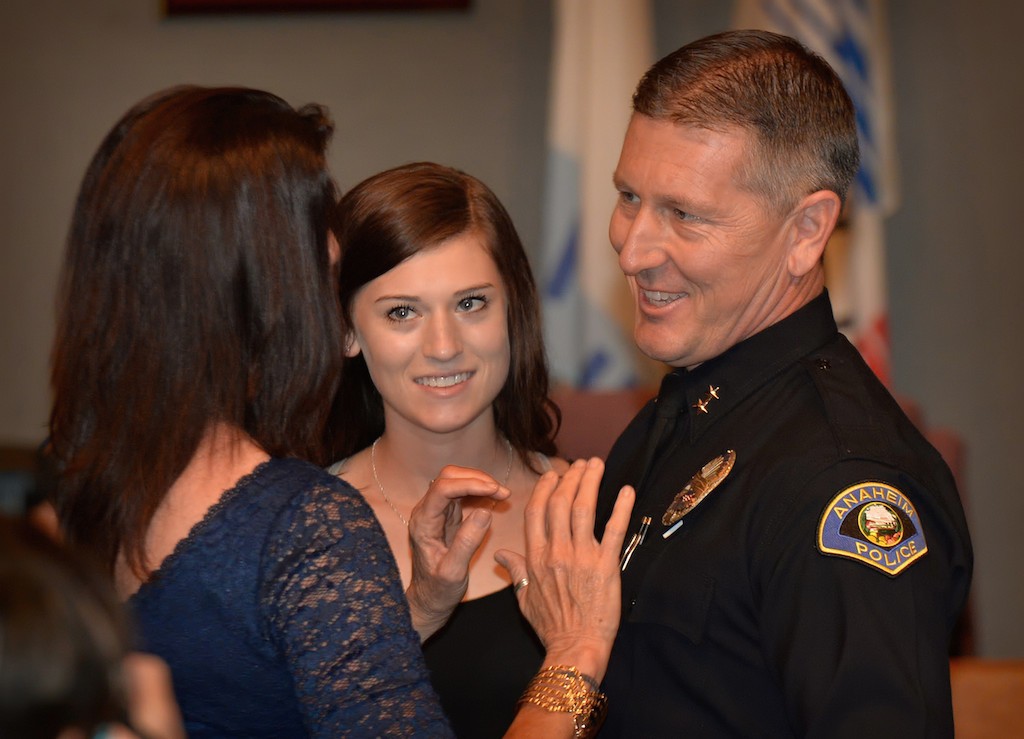 Dan Cahill, the new Deputy Chief for Anaheim PD, has his new badge pinned to him by his wife Ellyn, left, and one of his two daughters, Holly, during a swearing in ceremony at Anaheim City Hall. Photo by Steven Georges/Behind the Badge OC