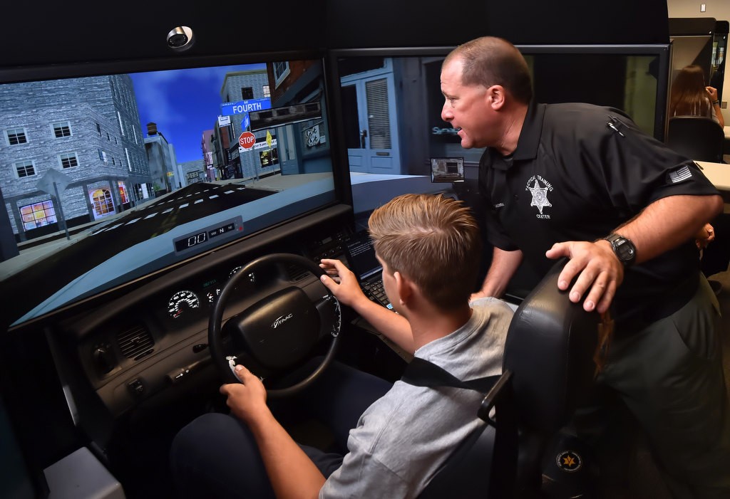 T. Maxwell of the OCSD Tactical Training Center gives a few tips to Curtis Parker during a police chase driving simulator. Photo by Steven Georges/Behind the Badge OC