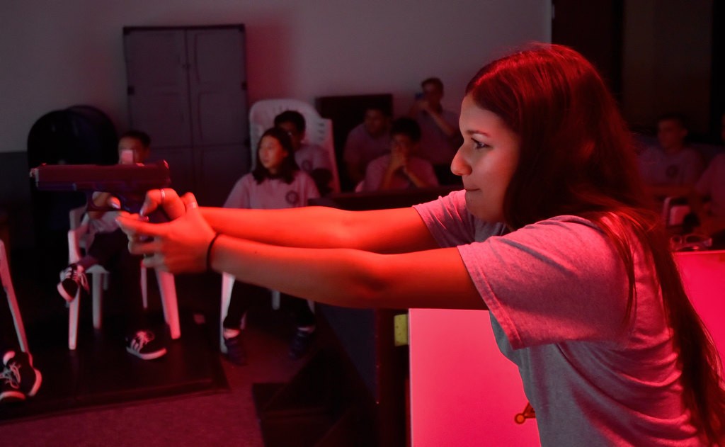 Makeyla Marquez, 15, of Mission Viejo aims a hand gun at the screen during a shooting simulator at the Orange County Sheriff's Training Center. Photo by Steven Georges/Behind the Badge OC