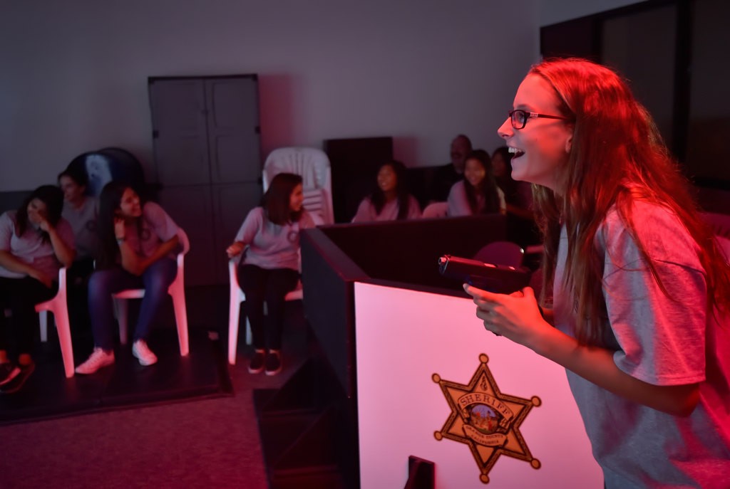 Zoey Lynd, 14, of Lake Forest, yells at the suspect on the screen to put their hands up during a shooting simulator the Orange County Sheriff's Training Center. Not all situations end up in a shooting and the simulator operator can even change the outcome depending on how an officer is handling the situation. Photo by Steven Georges/Behind the Badge OC