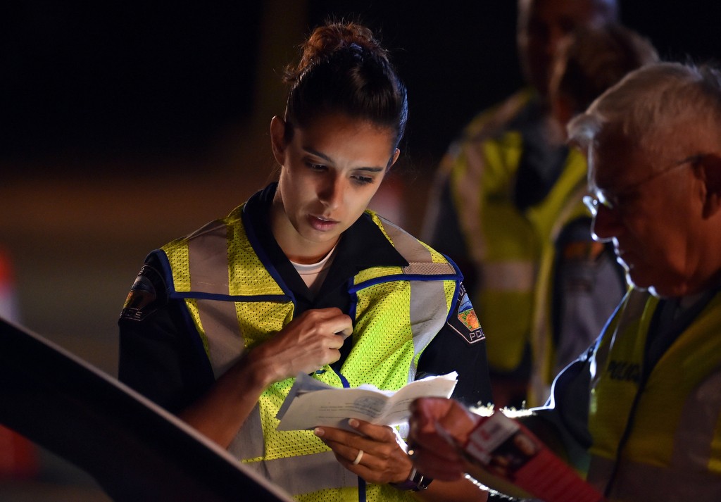 Tustin PD Officer Michelle Jankowski talks to drivers at a DUI checkpoint while Tustin PD Volunteer Rich Ruedas, right, hands out DUI pamphlets. Photo by Steven Georges/Behind the Badge OC
