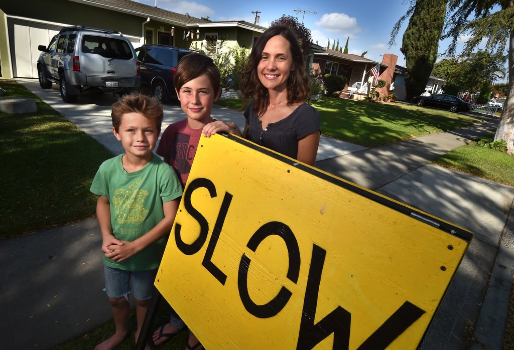 Eleven-year-old Jude Varieur with his brother, Jack Varieur, 9, left, and his mother Laurelin Varieur, stands next to one of the signs on his street telling drivers to slow down. Photo by Steven Georges/Behind the Badge OC