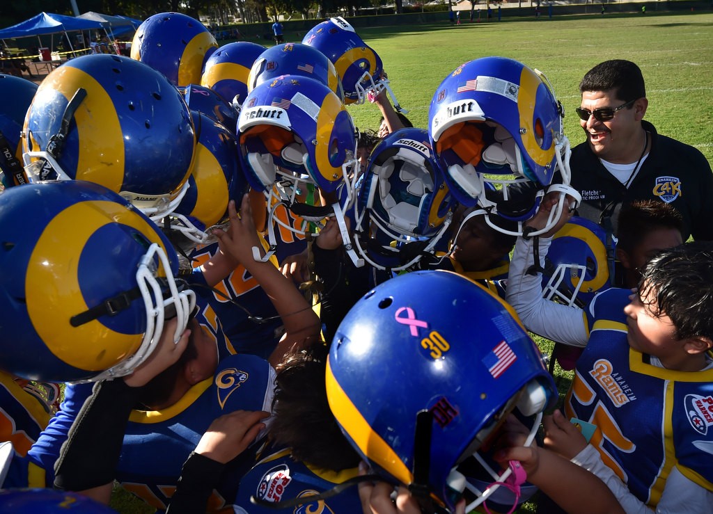 Anaheim PD Officer Eddie Fletcher, one of the coaches for the Anaheim Rams, joins the team in an end game cheer at the conclusion of a Pop Warner football game at Brookhurst Community Park in Anaheim. Photo by Steven Georges/Behind the Badge OC