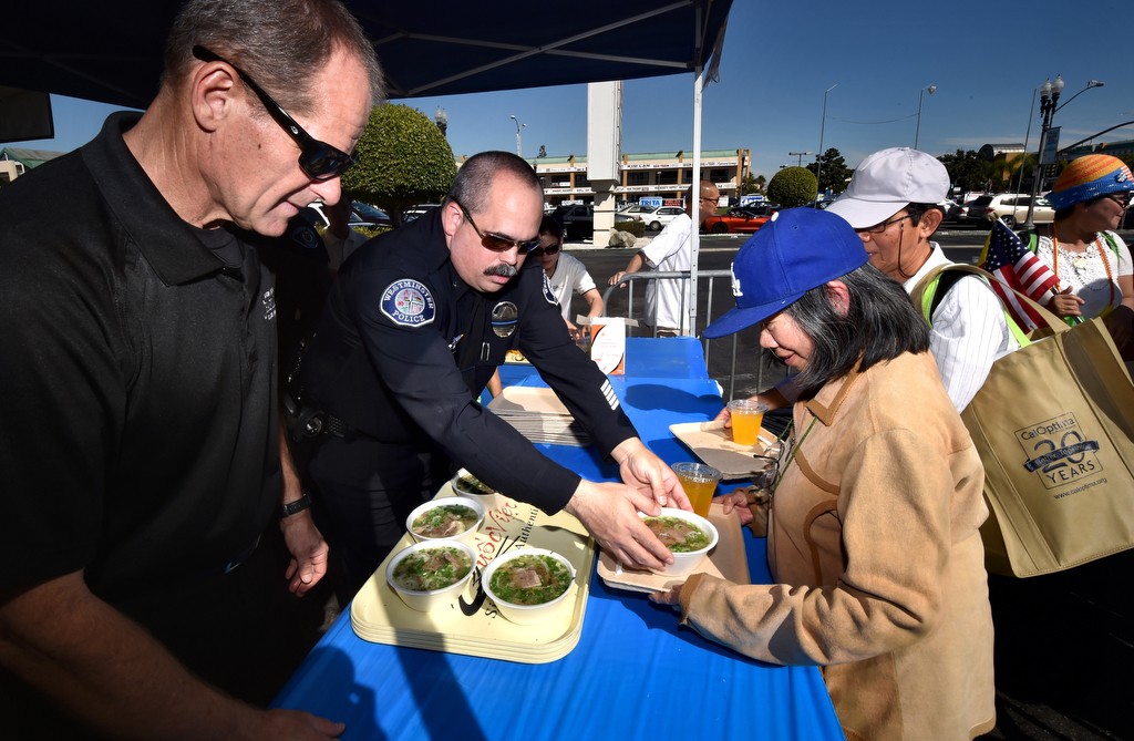 Garden Grove PD Chaplain James Scheller, left, and  Westminster PD Cmdr. Mike Chapman hand out bowls of free Pho (a type of Vietnamese soup) during the Viet-CARE Pho-Covery Celebration at the Asian Garden Mall in Westminster. Photo by Steven Georges/Behind the Badge OC