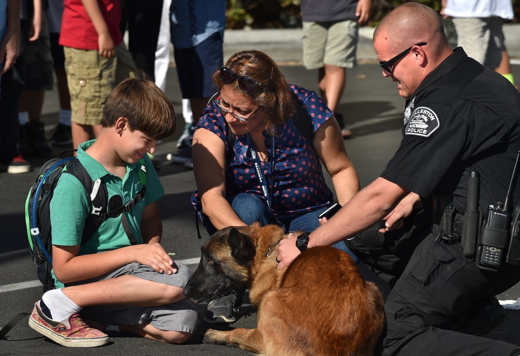 Jason Hoskinson, 11, an autistic student from Golden Hill Elementary School, kneels down to pet Rotar, a Fullerton PD K-9 during a tour of the police station. With him is Maria Fischer, an instructional aid with the school, and Fullerton PD Officer Jonathan Ferrell. Photo by Steven Georges/Behind the Badge OC