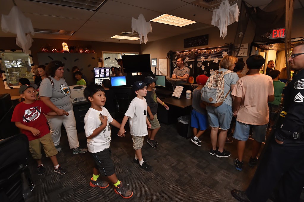 Autistic kids from Golden Hill Elementary School hold hands as they walk through Fullerton PD’s dispatch center already decorated for Halloween. Photo by Steven Georges/Behind the Badge OC