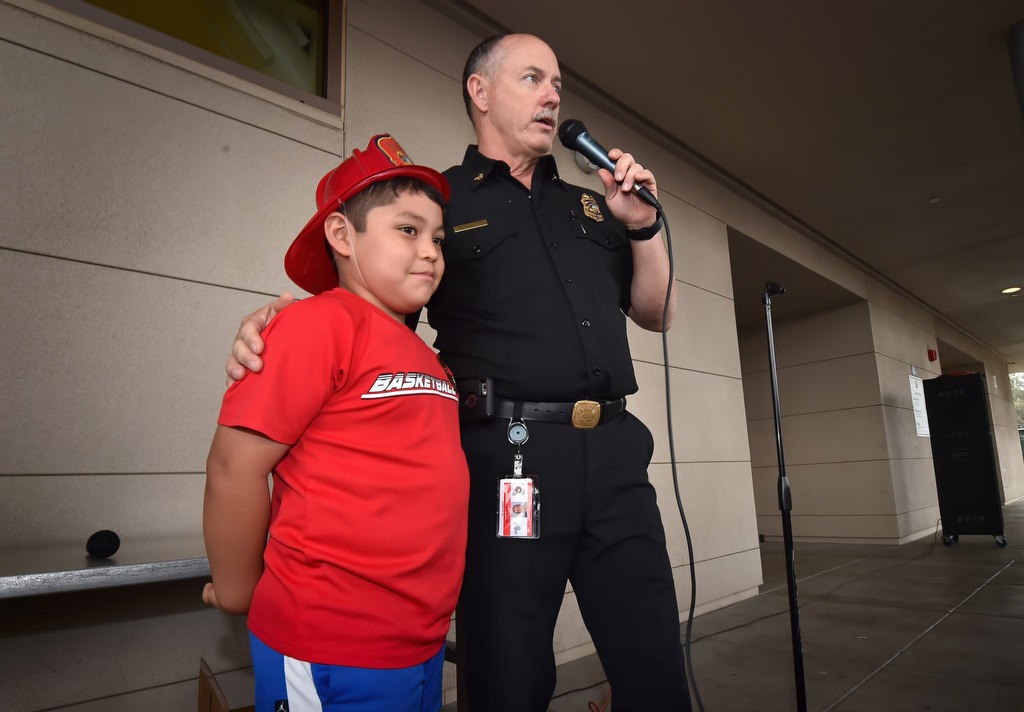 Anaheim Fire & Rescue’s Deputy Chief/Fire Marshal Rusty Coffelt stands with stands with 9-year-old Carlos Bermejo, who’s home was affected by the apartment complex fire last November, as the Anaheim Fire Department visits Edison Elementary School in Anaheim for Fire Prevention Week. Photo by Steven Georges/Behind the Badge OC