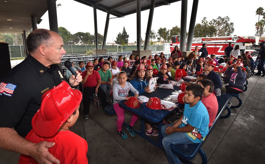 Rusty Coffelt, deputy chief/fire marshal for Anaheim Fire & Rescue, stands with 9-year-old Carlos Bermejo, who’s home was affected by the apartment complex fire last November, as the Anaheim Fire Department visits Edison Elementary School in Anaheim as they hand out smoke alarms and offering home safely visits for Fire Prevention Week. Photo by Steven Georges/Behind the Badge OC