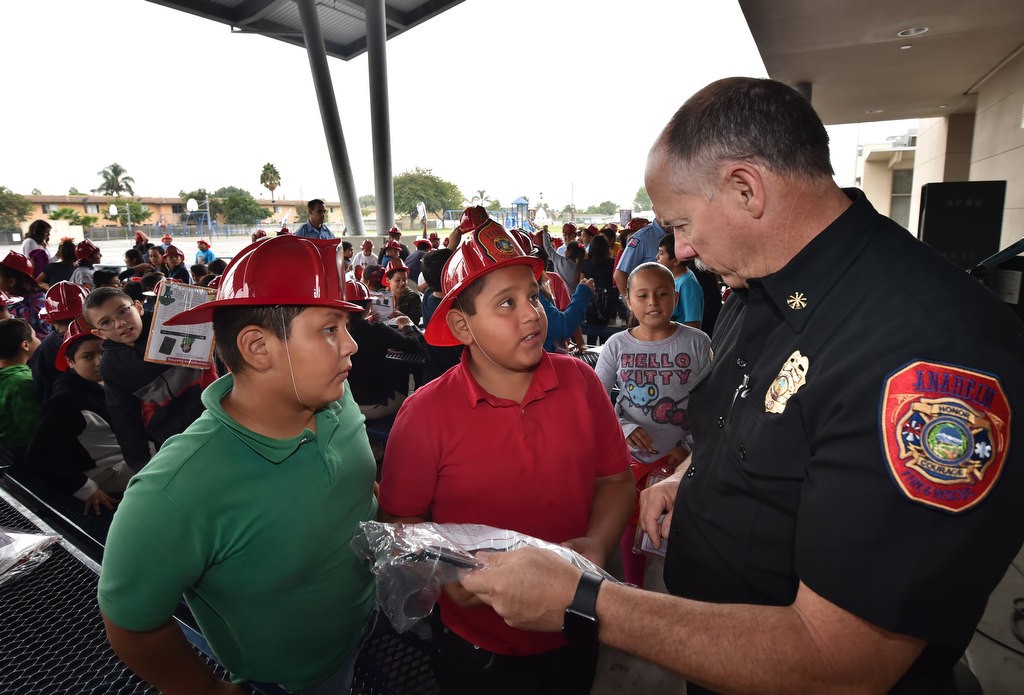 Anaheim Fire & Rescue’s Deputy Chief/Fire Marshal Rusty Coffelt talks to 9-year-old Edison Elementary School students Andres Tlatempa, left, and Omar Calderon about the importance of installing the free smoke alarms the fire department gave the kids during a Fire Prevention Week assembly. Photo by Steven Georges/Behind the Badge OC